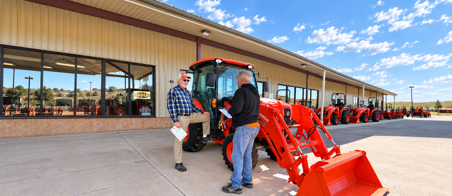 Two people beside an orange tractor at a dealership
